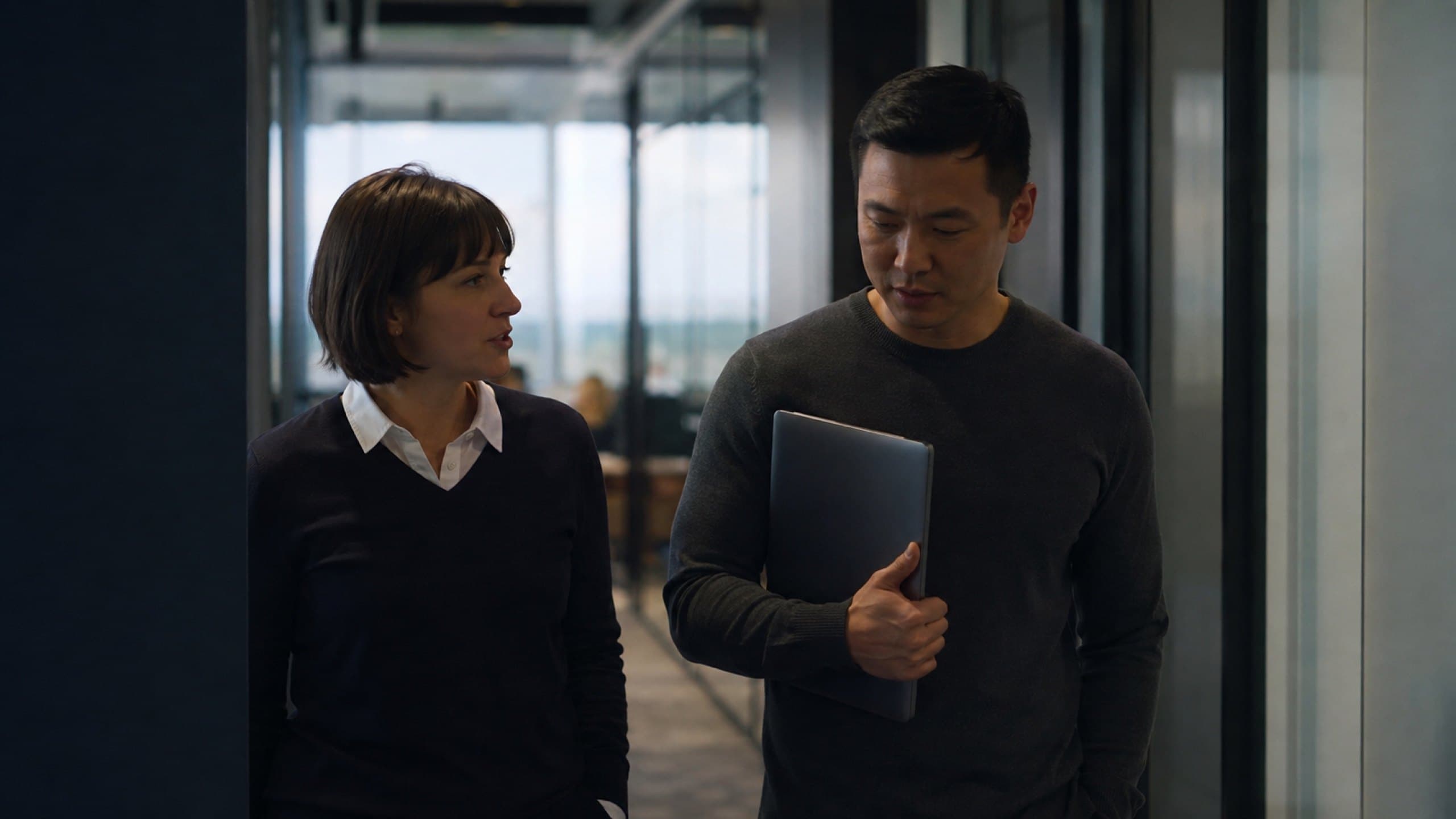 Colleagues talking in a hallway between meetings